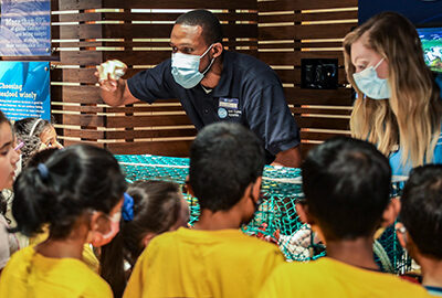 A group of students listening to an Aquarium educator.