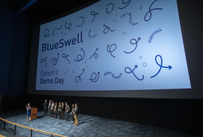 several people standing on stage in front of a presentation screen