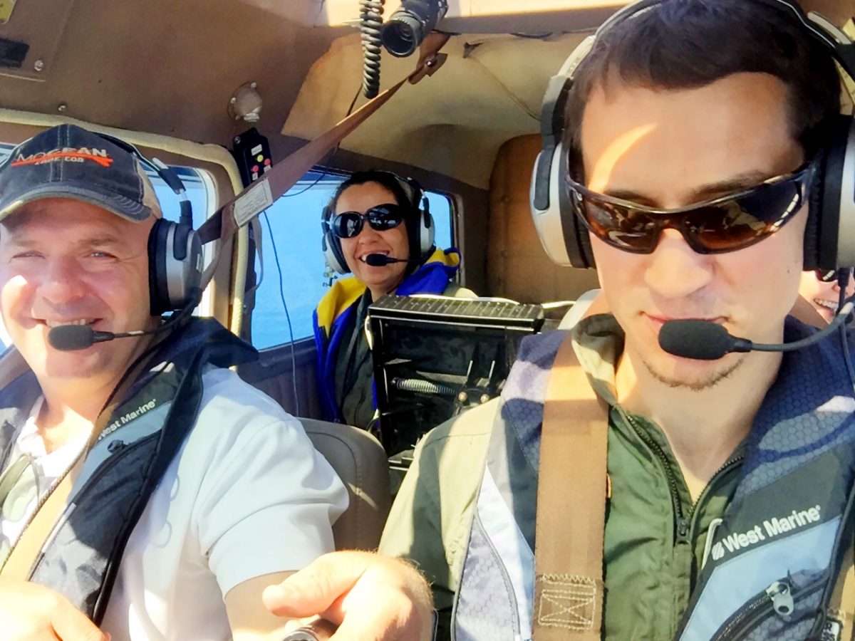 Three people inside an airplane cockpit.