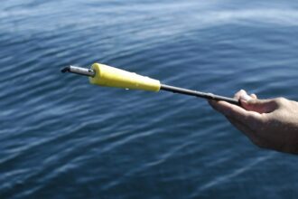 Person's hand holding a short pole with a yellow tip