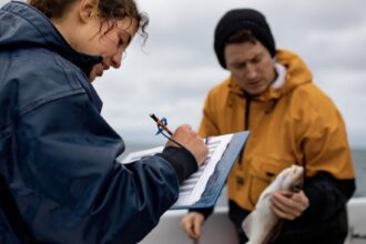 woman with a clipboard and man holding a fish