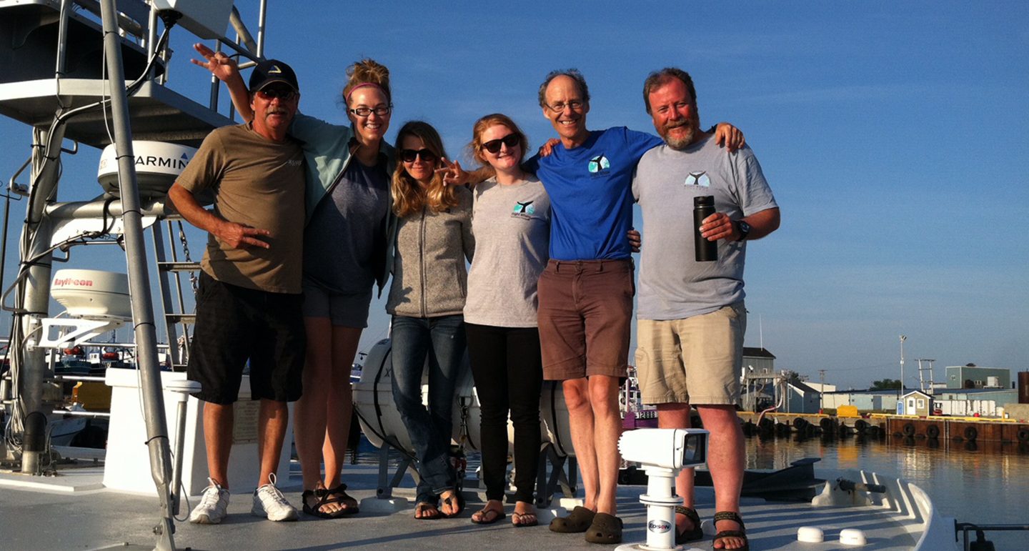 Six people posing on the deck of a boat