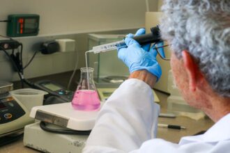 A person performing a test of a water sample in a beaker