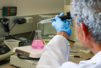 A person performing a test of a water sample in a beaker