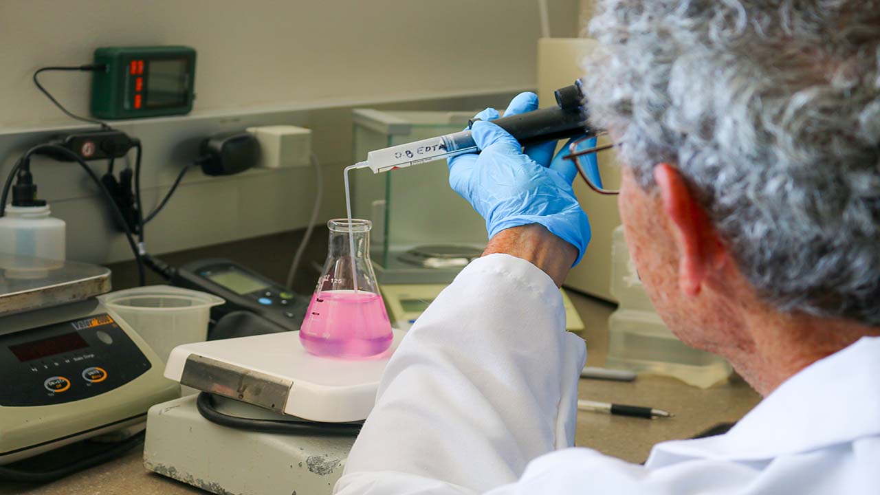 A person performing a test of a water sample in a beaker