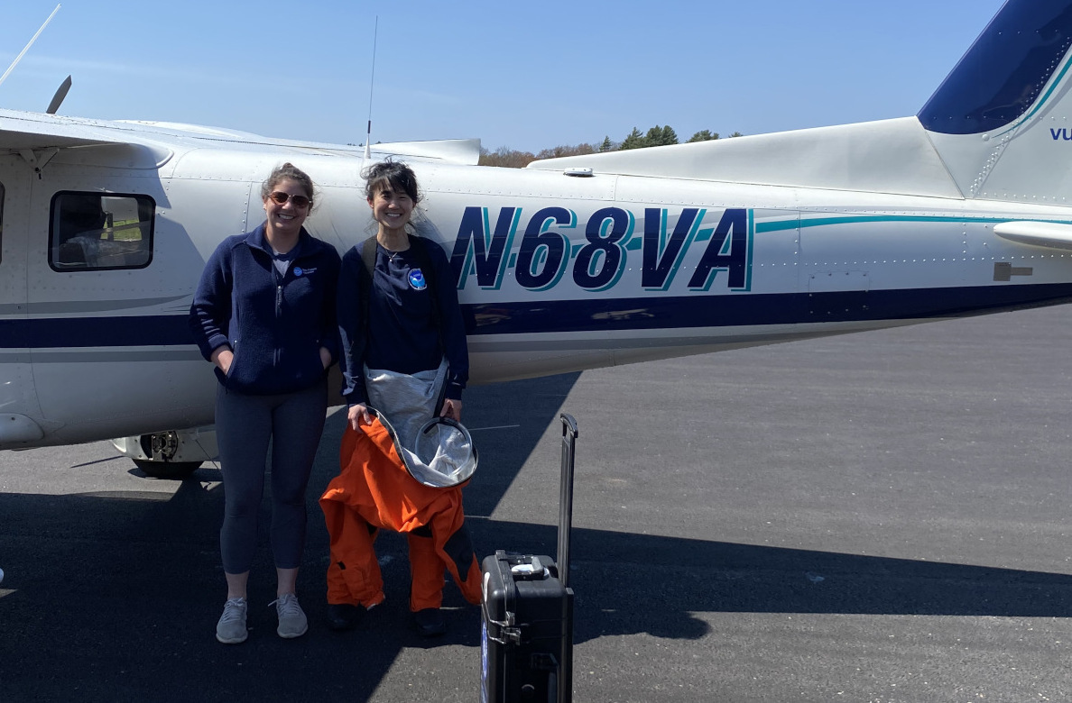 two women standing in front of a small plane
