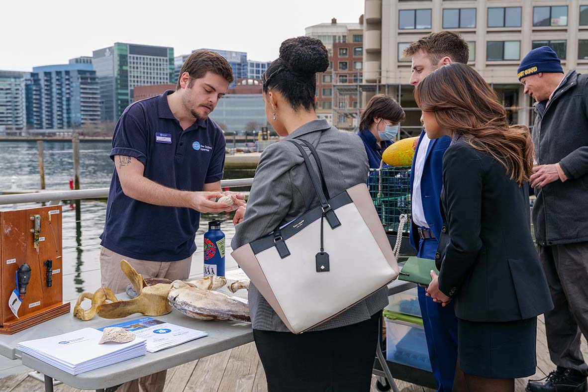 A member of the Aquarium staff meeting with a group on the pier.