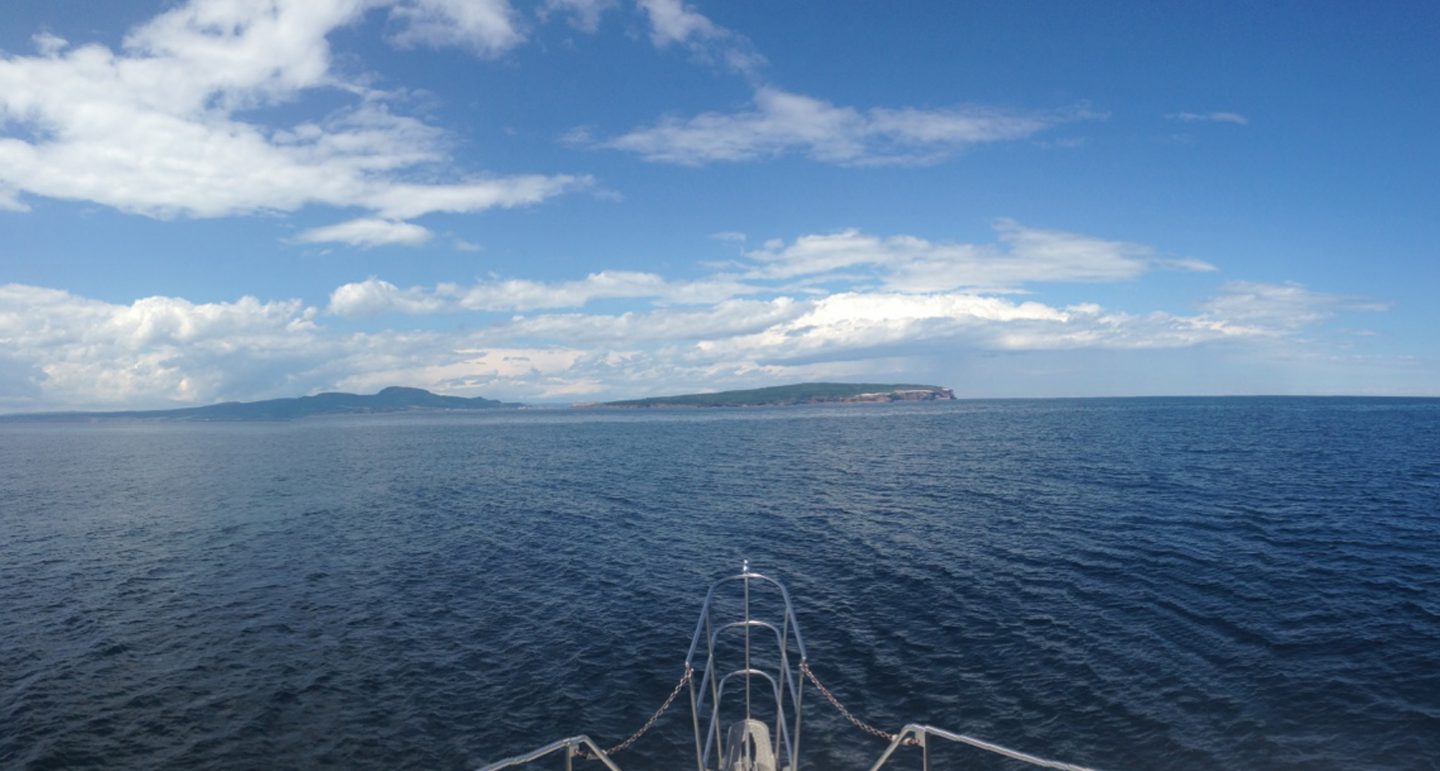 Point of view taken from bow of a ship with land in the far distance