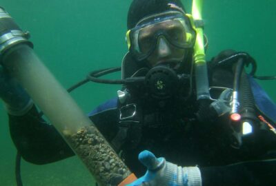 A scuba diver holding a tube of collected sediment to measure sequestered carbon