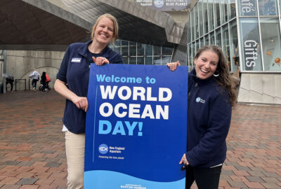 Two Aquarium staff members holding a sign that says 