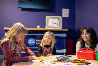 Young learners sit with an Aquarium educator at Exploration Station