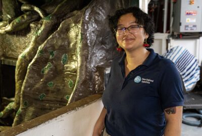 A person in a blue Aquarium shirt standing beside a tank