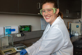 A person in a lab coat and bedazzled safety glasses