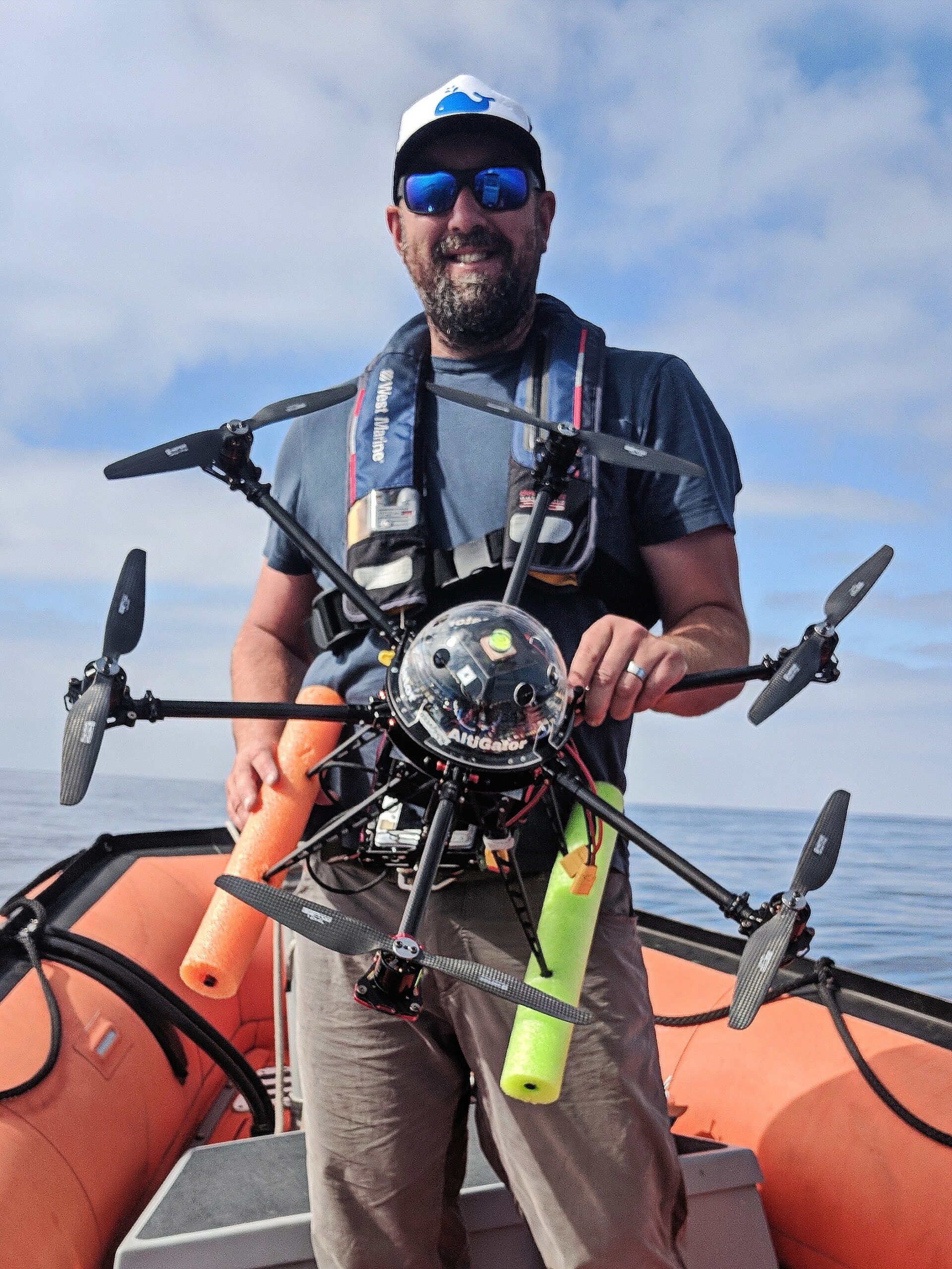John in an orange inflatable boat holding a drone
