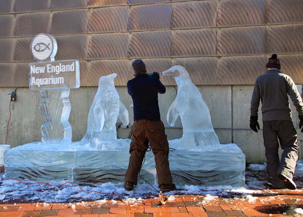 A person carving an ice sculpture of penguins