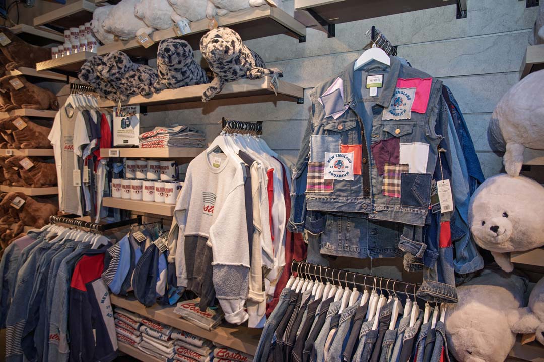 Retail display with clothing, plush seals, and New England Aquarium-branded items.