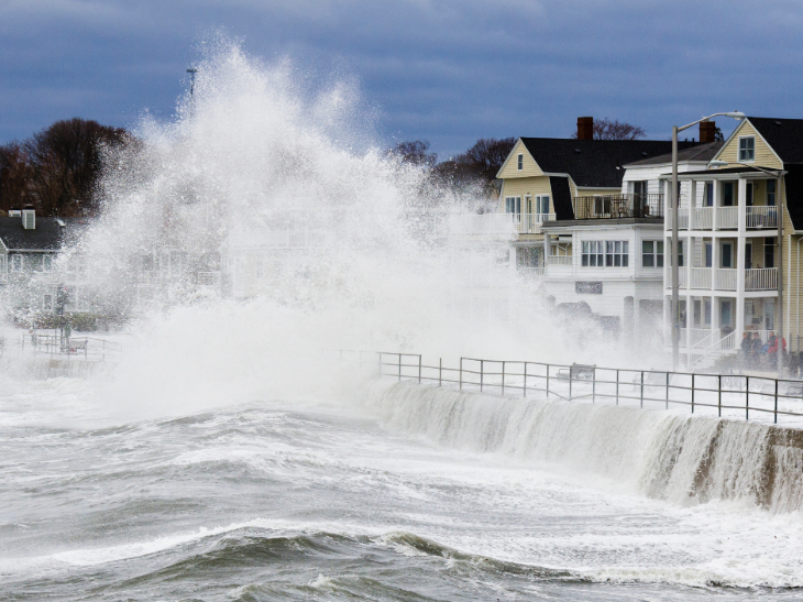 A winter storm causing ocean waves to hit a seaside barrier near coastal houses