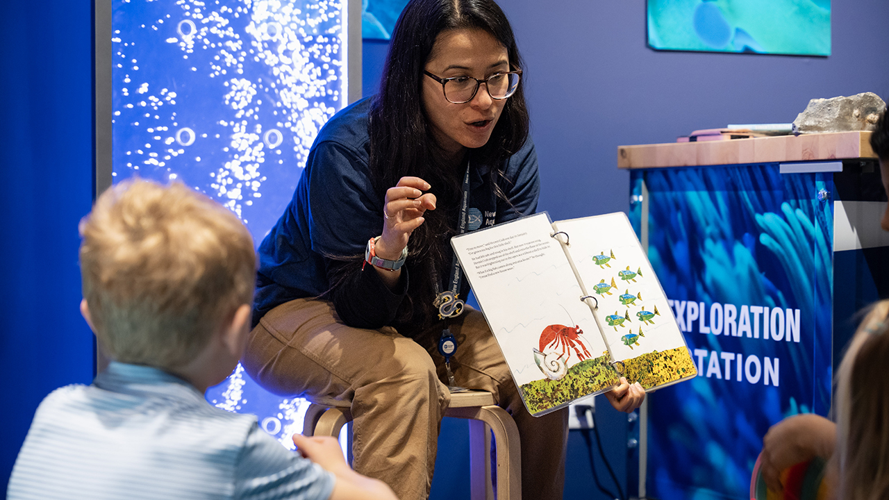 A person reading a storybook to young children