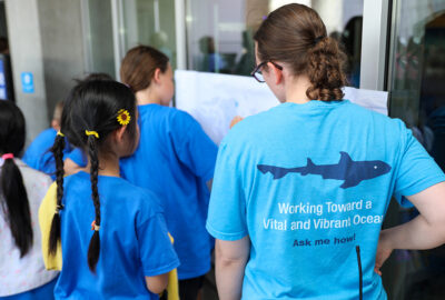 A staff member talking with a young guest at an event at the Aquarium