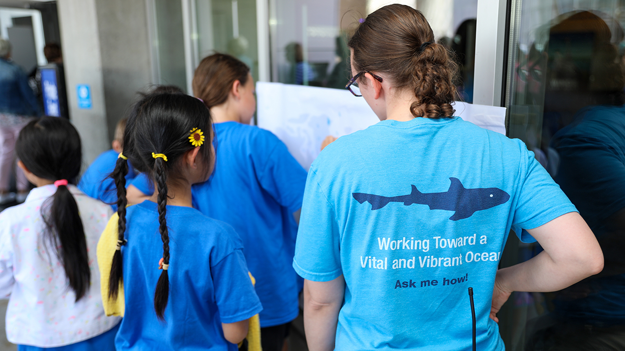 A staff member talking with a young guest at an event at the Aquarium