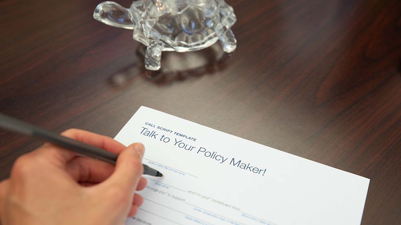 A person writing a letter on a desk