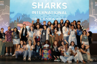 A group of people in front of a Sharks International banner