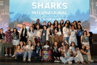 A group of people in front of a Sharks International banner