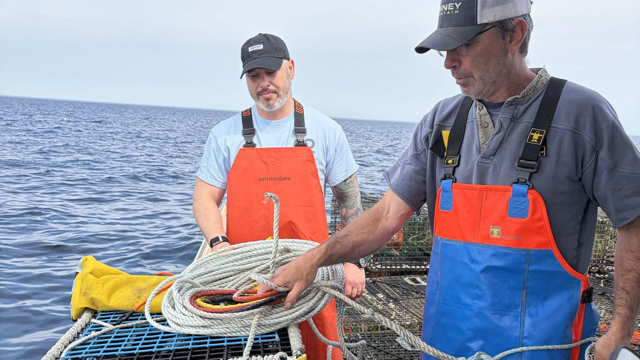 Two people in protective work gear on a fishing boat